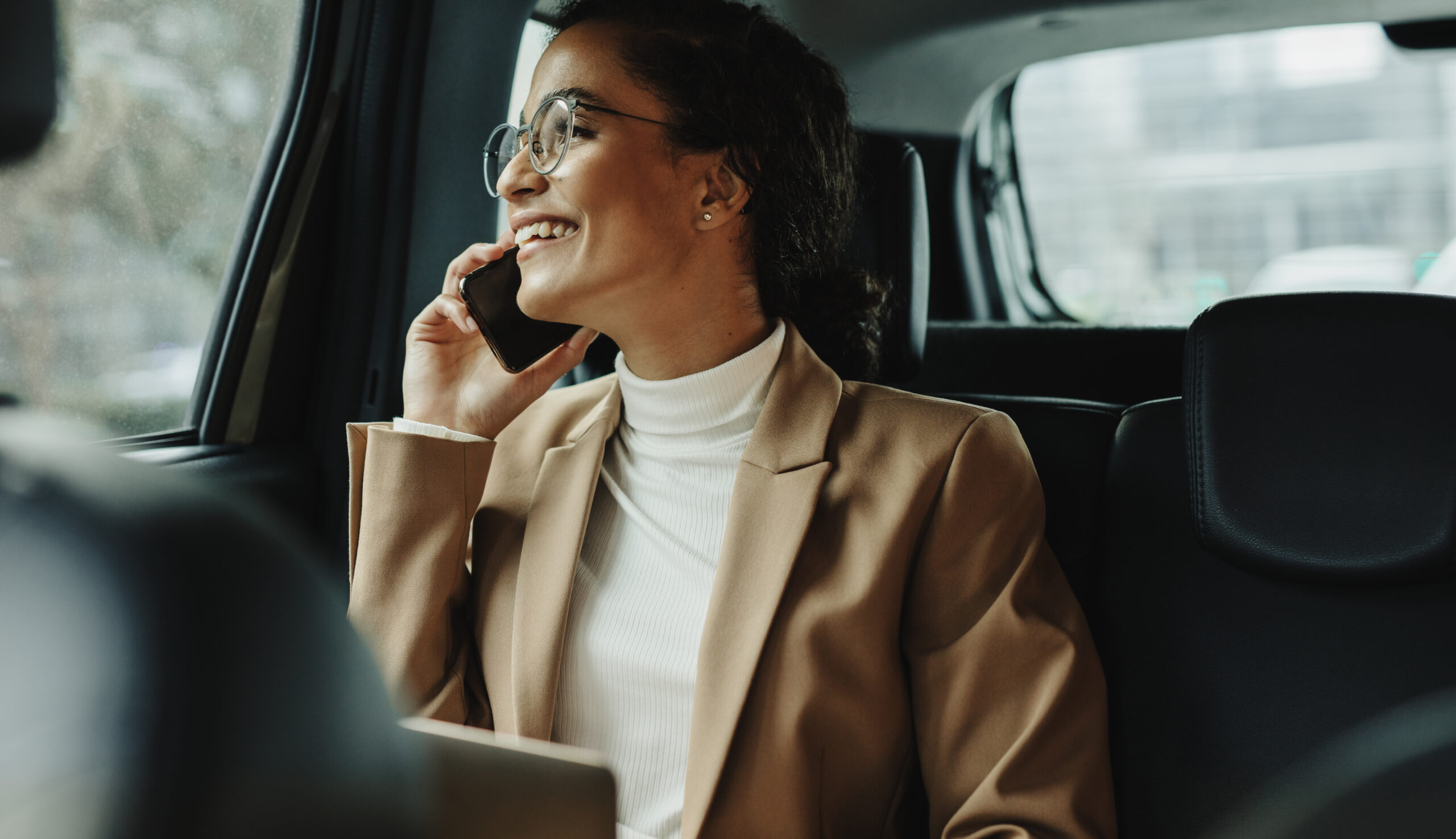 Businesswoman,Sitting,On,Backseat,Of,Her,Car,And,Talking,On