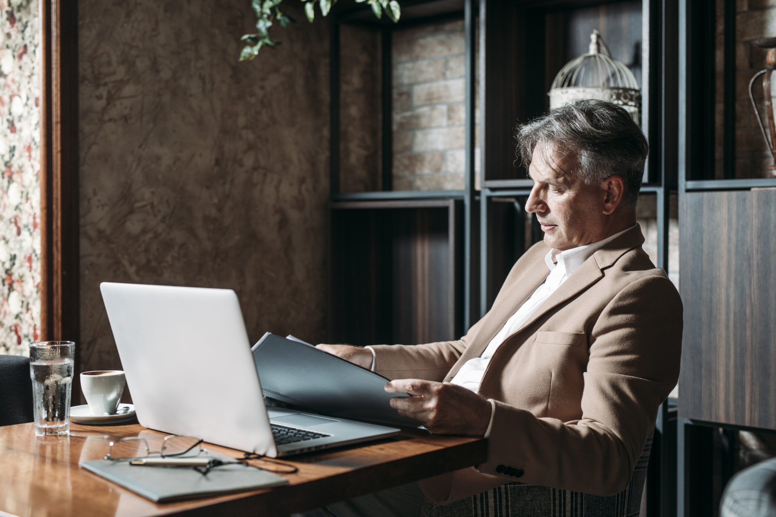 Handsome,Caucasian,Grey-haired,Businessman,Sitting,At,Cafe,And,Reading,Documents.